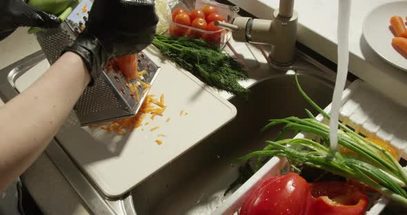 Grating Fresh Carrot On The Cutting Board By The Sink With Vegetables