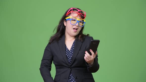 Mature Beautiful Asian Businesswoman Using Phone While Wearing Many Eyeglasses As Funny Concept