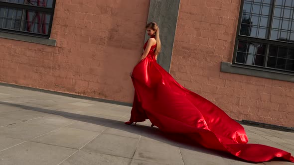 Young Gorgeous Woman in Long Red Dress Walking in the City