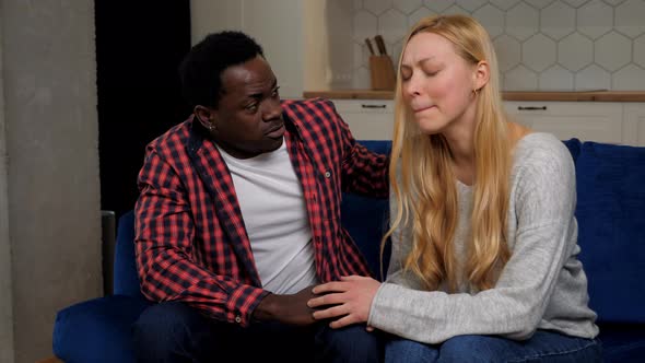 African American Man Comforting Upset Woman Sitting on Couch at Home Kitchen