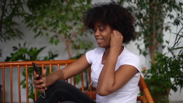 Side View of Positive Young AfricanAmerican Young Woman Putting on Headphones and Turns Favorite