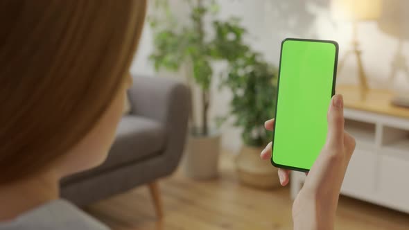 Handheld Camera Back View of Blond Man Holding Chroma Key Green Screen Smartphone Watching Content