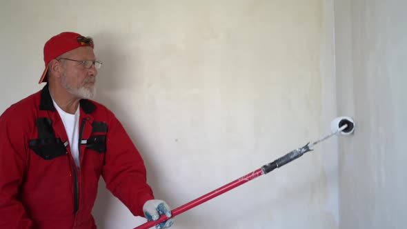 Whitewasher Man with Ladder Painting a White Ceiling with Paint Stick Roller in Empty Renovation