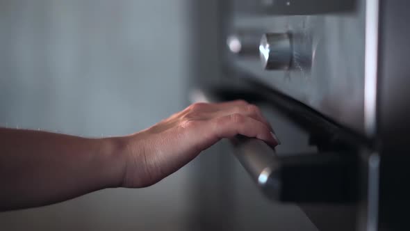 Woman Opens an Oven in Kitchen Put Food for Baking for dinner.Modern Equipment.