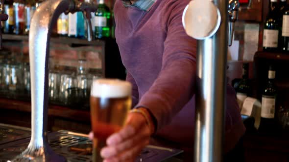 Barman filling beer from beer pump