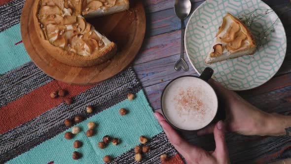 Top View of the Table De Lies an Apple Pie and a Cup of Coffee. Denny's Hands Hold a Mug Over 