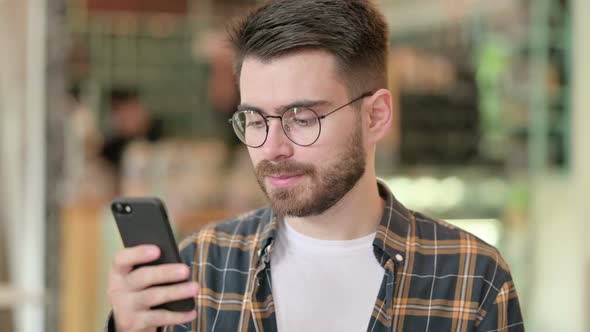 Portrait of Positive Young Man Using Smartphone