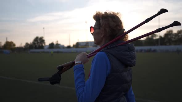 Senior Woman Training with Walking Poles at Stadium