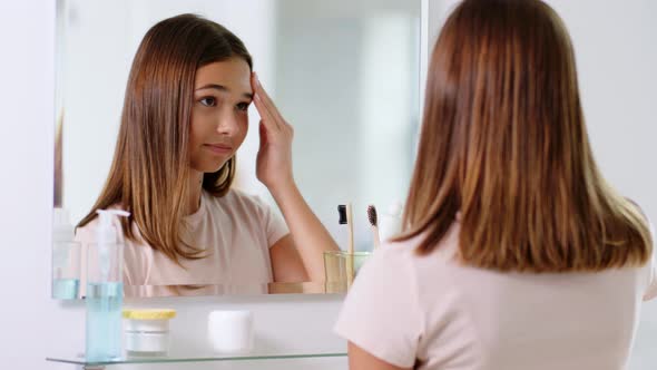 Teenage Girl Applying Moisturizer at Bathroom