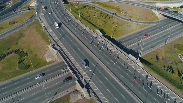 Aerial Drone Footage. Marathon Running Group on the Road Junction, Close Up Static Shot