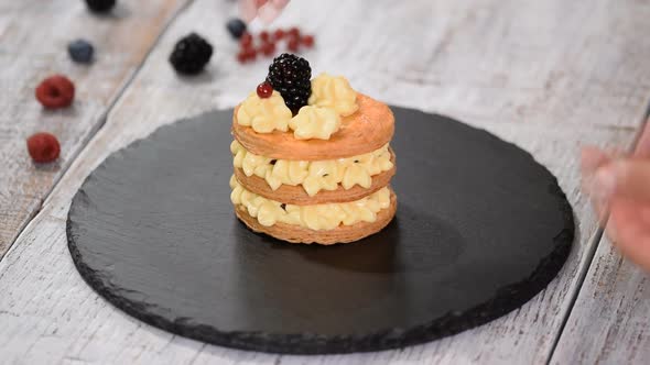 Pastry chef making French Mille Feuille with custard and berries.