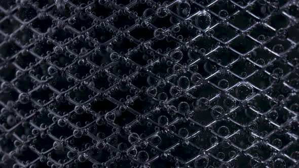 Metal Mesh Covered with Oxygen Bubbles in Water on a Black Background