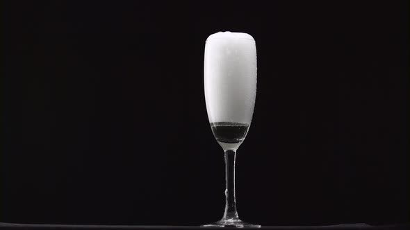 Champagne Is Poured Into the Misted Glass on a Thin Stalk. Black Background