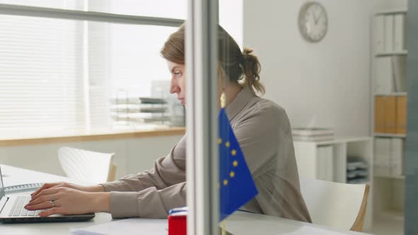 Female Visa Officer Working on Laptop and Checking Documents