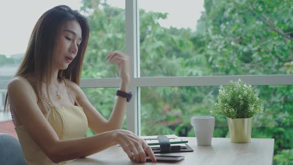 Mobile payment concept : Young beautiful Asian woman enjoying a relaxing moment working and using mo