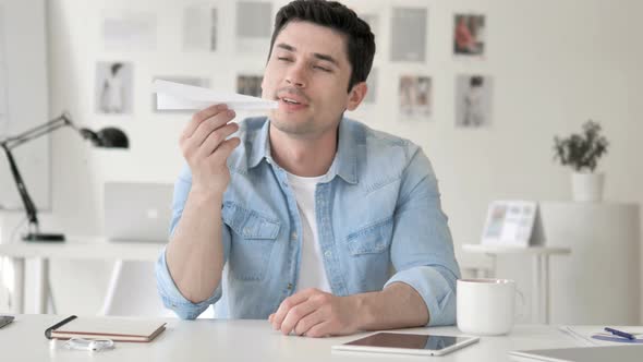 Pensive Young Man Holding Paper Plane