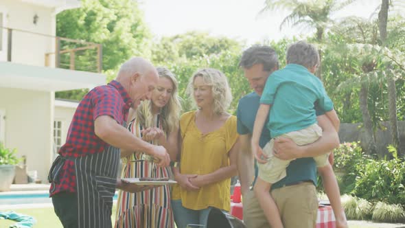 Happy caucasian family having barbecue and eating in garden