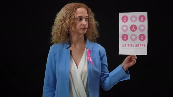 Portrait of Serious Woman Looking at Camera Holding Breast Cancer Placard in Hand