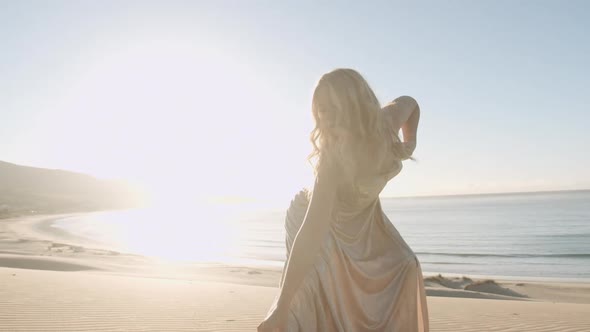 Young Dancing Woman In Gold On Beach