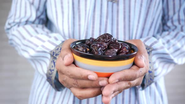 the Concept of Ramadan Hand Holding a Bowl of Date Fruits