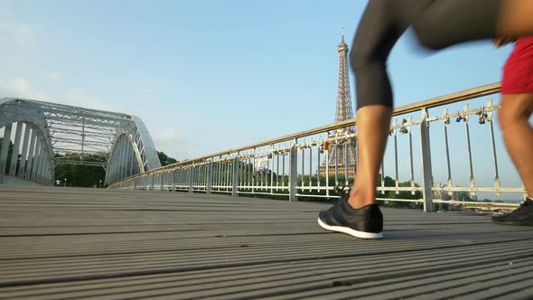 A couple running across a bridge with the Eiffel Tower