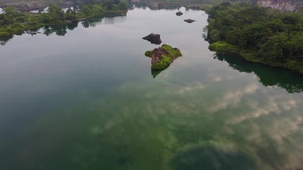 Aerial fly over quarry pool with clear water reflection