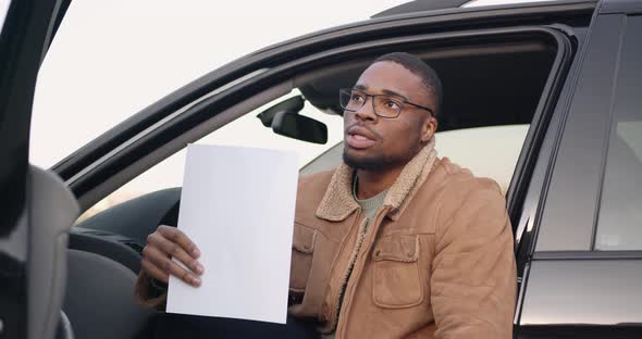 Male Driver Behind the Wheel with Sheet of Paper