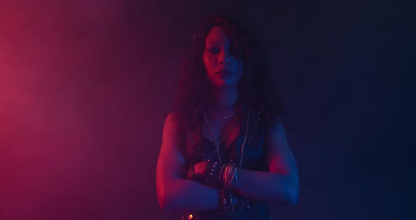 Black Woman with Her Arms Crossed Is Standing in Colorful Lights and the Smoke