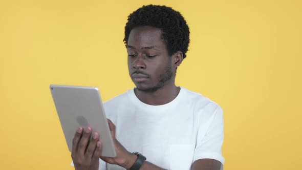 African Man Excited for Success While Using Tablet Yellow Background