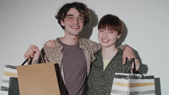 Young Cheerful Couple Posing with Shopping Bags in Studio