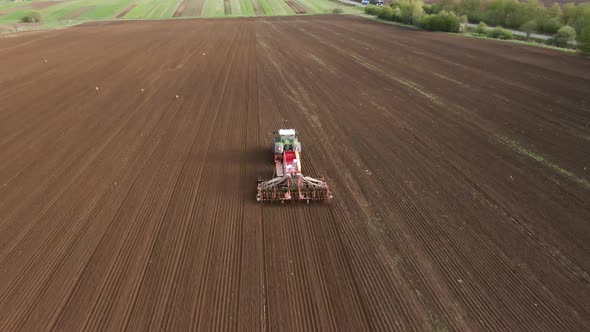 Tractor in Working in the Field. Tractor with a Modern Sowing Seeds Machine in a Newly Plowed Field