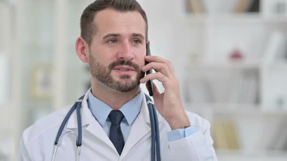 Portrait of Cheerful Male Doctor Talking on Smartphone