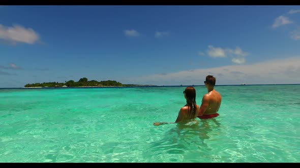 Boy and girl sunbathe on tranquil seashore beach trip by clear ocean and white sand background of th