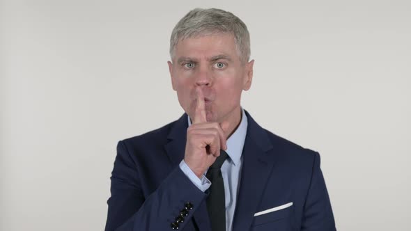 Senior Businessman Gesturing Silence, Finger on Lips