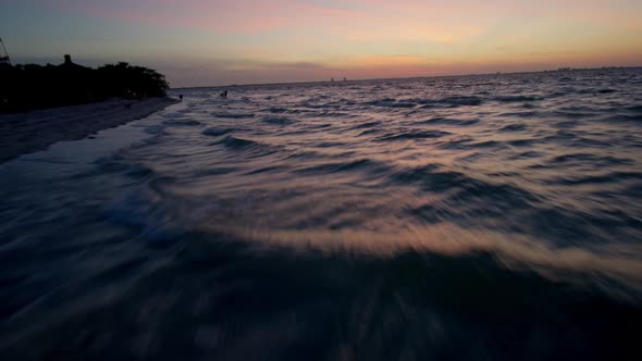 Low fast flight over the water by the shore in early dawn rising up to approach the Sanibel Island l