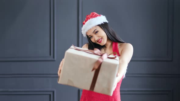 Adorable Female Santa Claus Gives Big Gift Box in Christmas Time at Studio Medium Shot