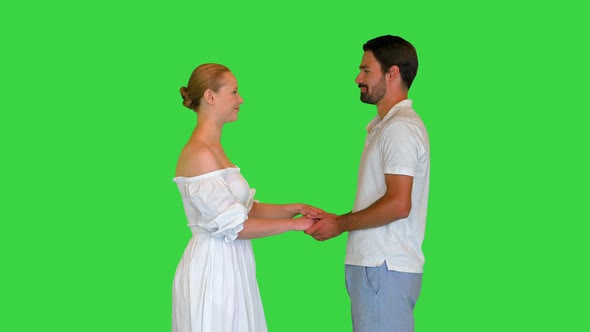 Young Couple in Love Holding Hands Looking at Each Other on a Green Screen Chroma Key