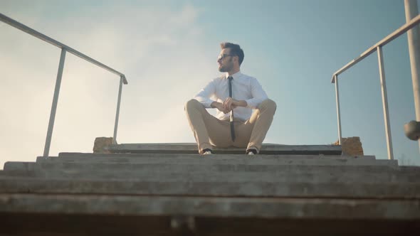 Businessman Relaxing And Sitting On Steps. Man Worker Enjoying Break After Hard Office Work Day.