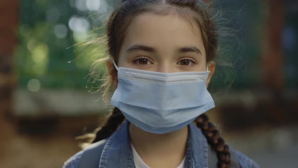 Little Smart Girl Standing on Street in Surgery Mask Turn Around Looking at Camera Close Up