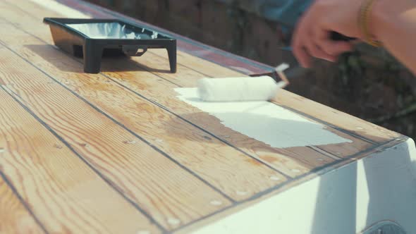 Applying white primer paint on wooden planks of wood boat wheelhouse cabin