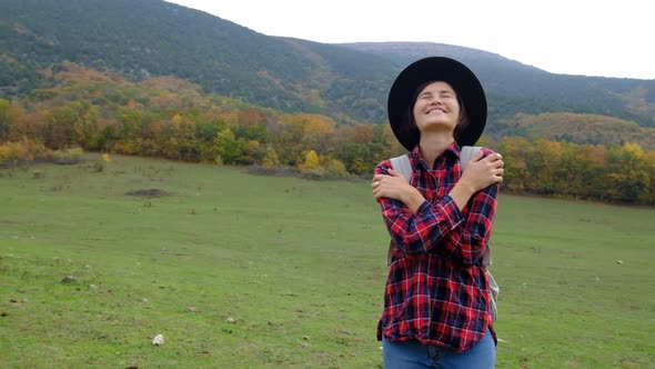 Woman Traveler with Backpack and Hat and Looking at Amazing Mountains