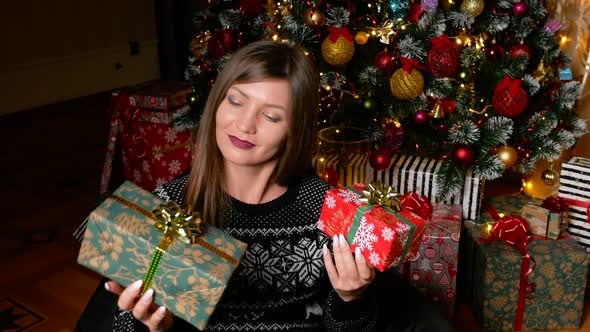 Young Asian Woman Selects and Shake Christmas Gift