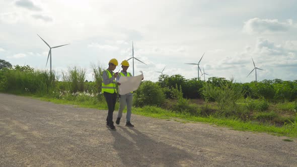 Teamwork of Asian windmill engineer group, worker working, holding a plan on site at wind turbines