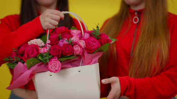 Unrecognizable Young Slim Woman Giving Twin Sister Flowers in Basket