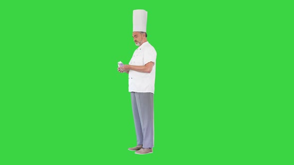 Senior Cook in Uniform Counting Money on a Green Screen Chroma Key