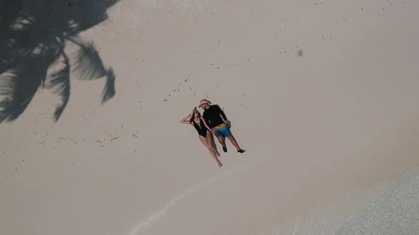 Top view with young couple laying on the beach