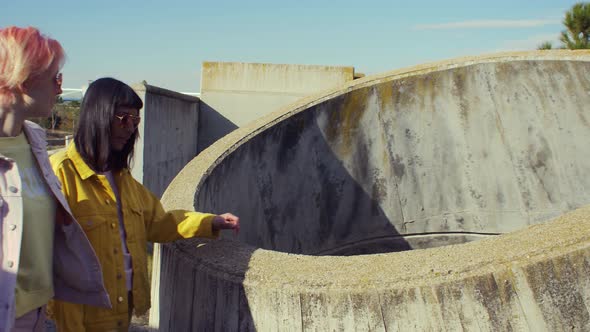 Two fashionable women looking inside of a cement building