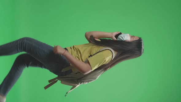 Asian Girl Student Wearing A Mask And Talking On Mobile Phone While Running On Green Screen