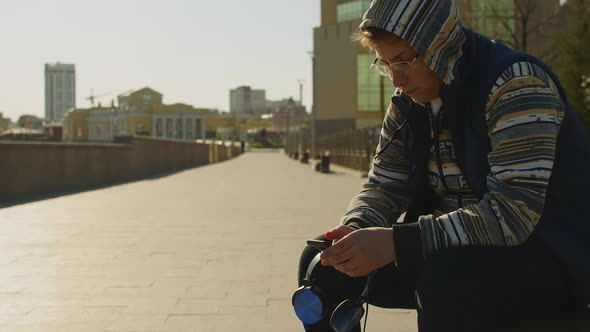 Teenage Boy with Smartphone and Headphones  He Chatting with Friends Outdoor