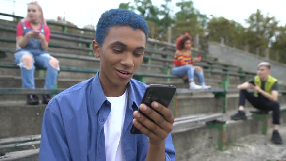 Surprised College Student Browsing Smartphone Internet Sitting Outdoors, Sale